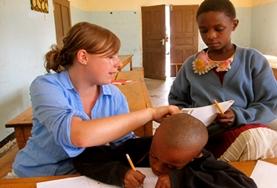 Vrijwilligerswerk en stage in Tanzania:Een lesgeef vrijwilliger in Tanzania helpt de kinderen bij hun huiswerk. Een lesgeef vrijwilliger in Tanzania helpt de kinderen bij hun huiswerk.